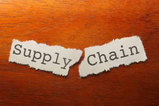 Piece of paper torn into two with supply chain written on it to depict disruptions